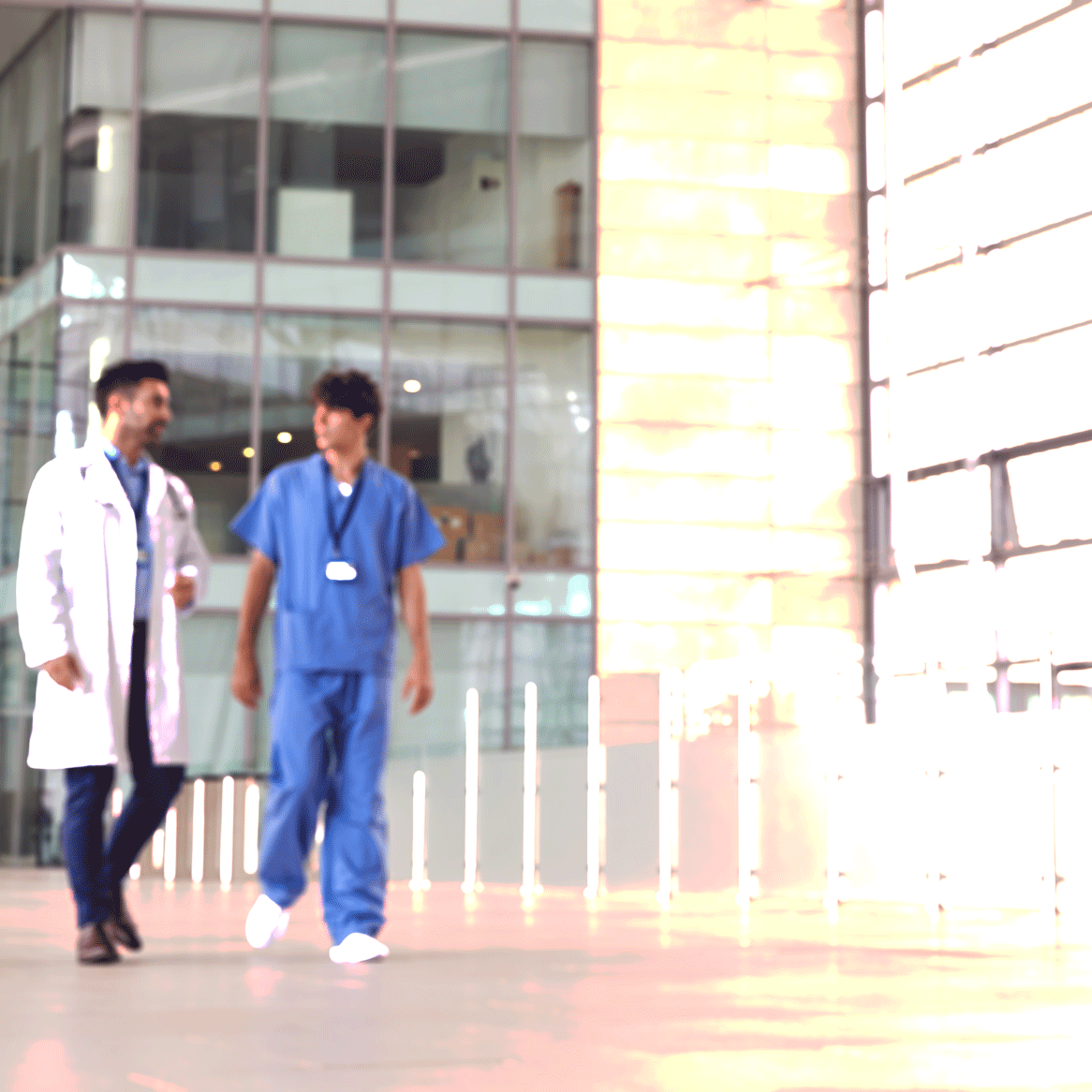 male-medical-staff-talking-as-they-walk-through-lo-T6D2VL7